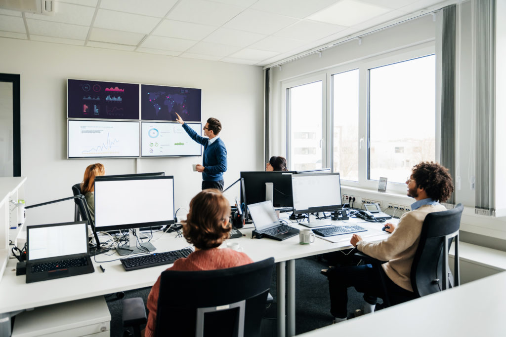 Office With People Reviewing Data On Monitors