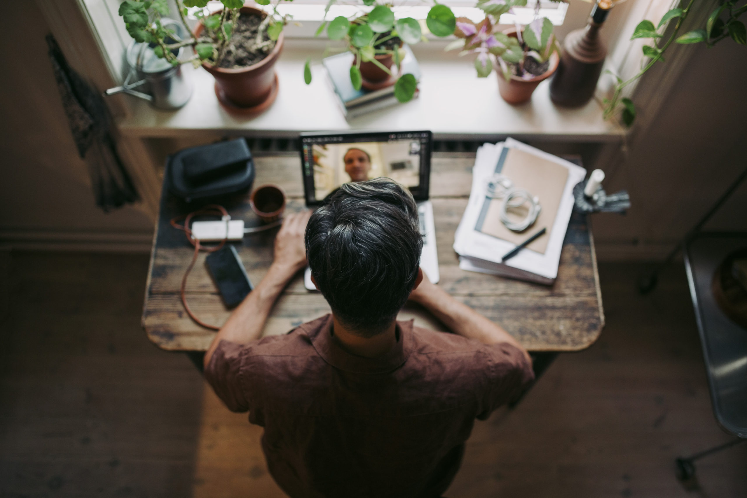Directly above shot of businessman on video call through laptop with male colleague during remote onboarding
