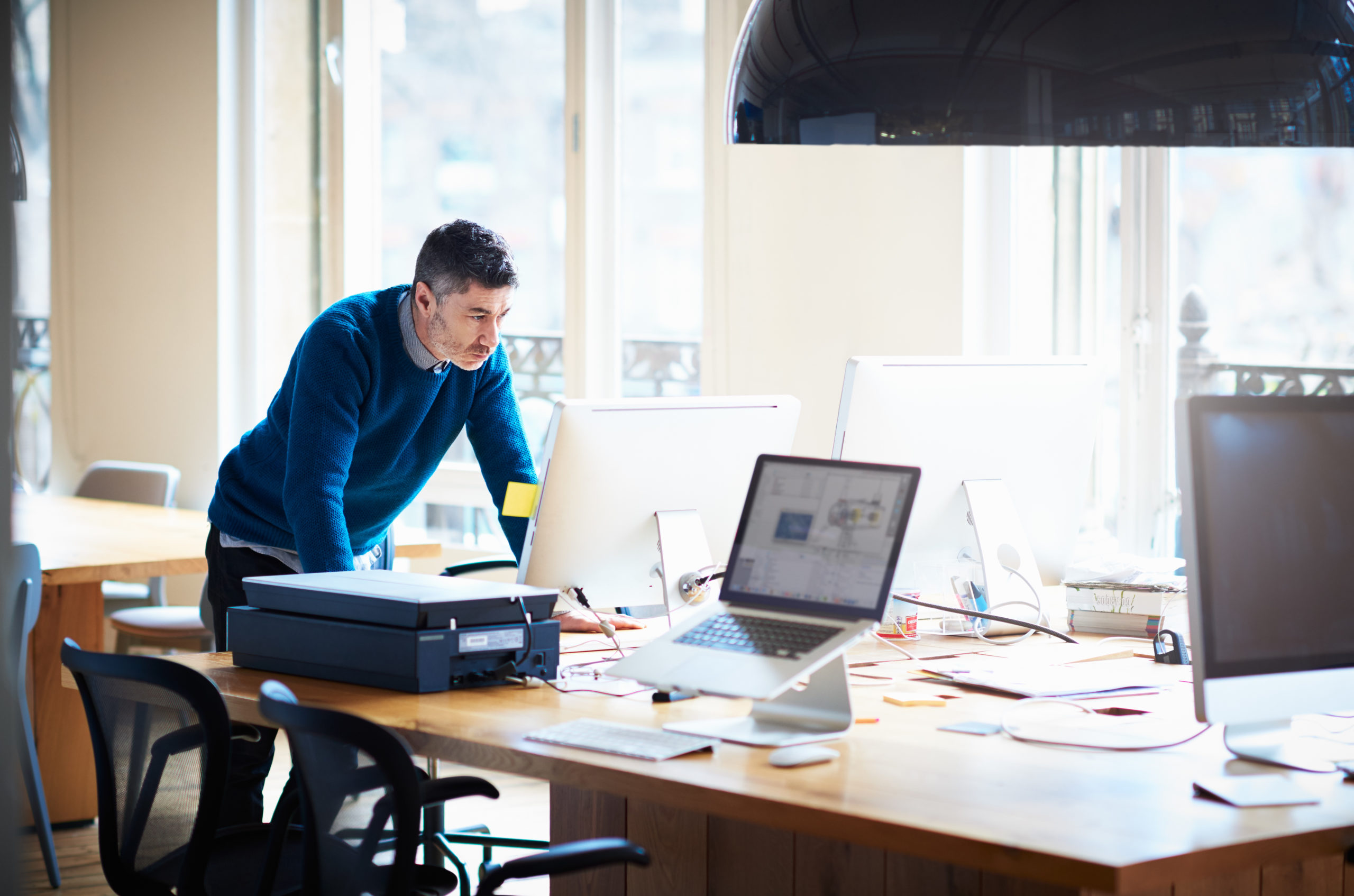 Small business owner standing by computer screen in a high-tech office.