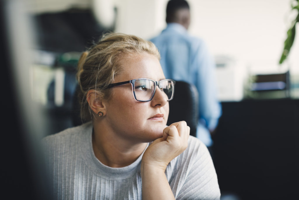 Female entrepreneur with hand on chin looking away in office