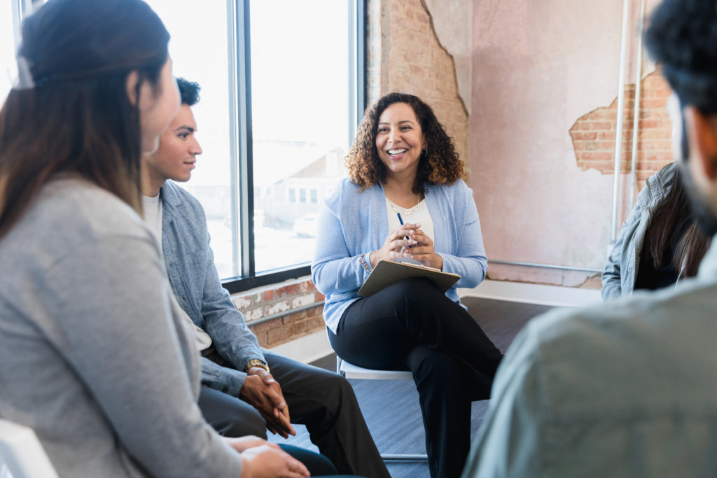 adult female manager smiles at her team and encourages their ideas.