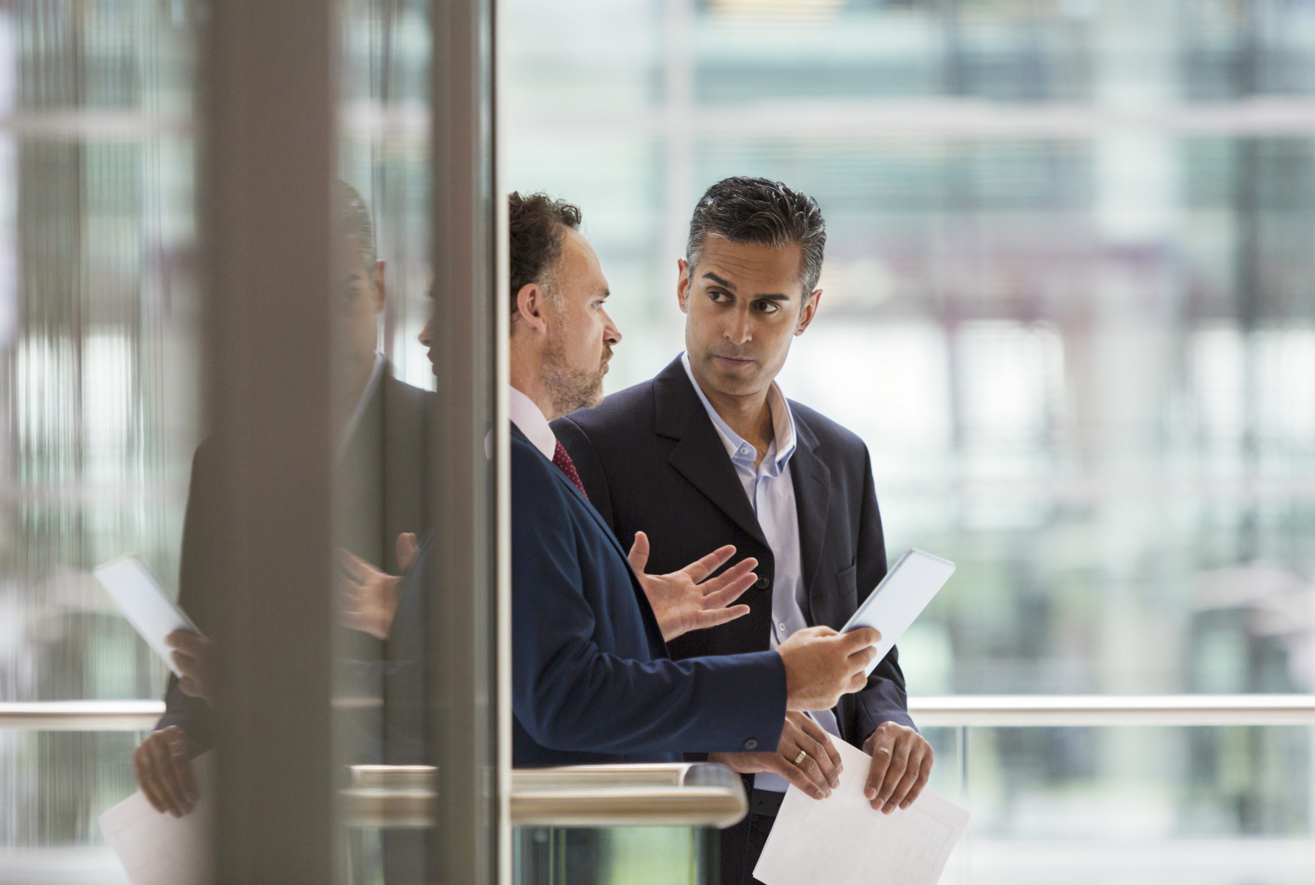 Businessmen discussing employment lawsuit on office balcony