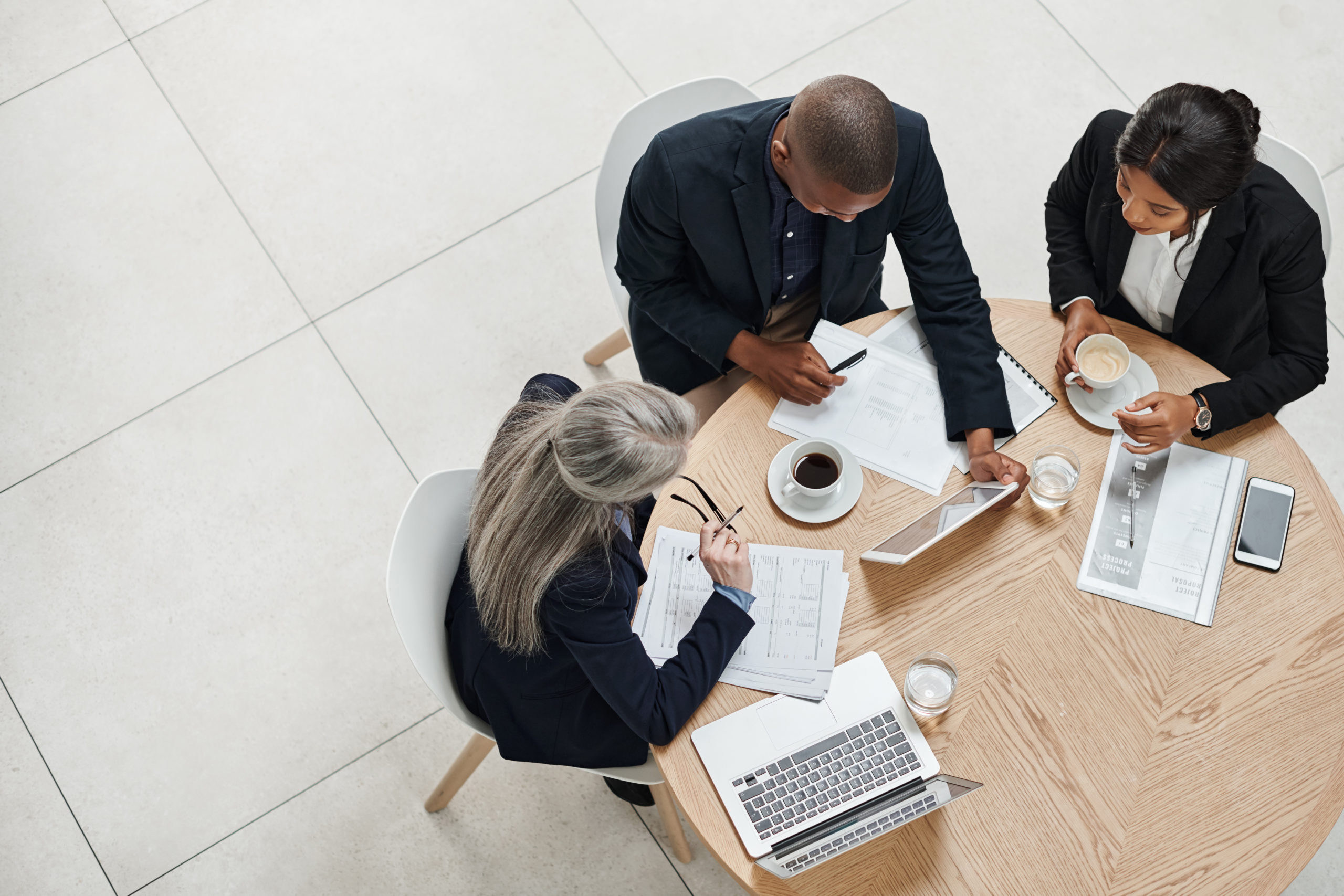 High angle shot of a group of businesspeople having a meeting to decide between in-house HR or outsourced HR.