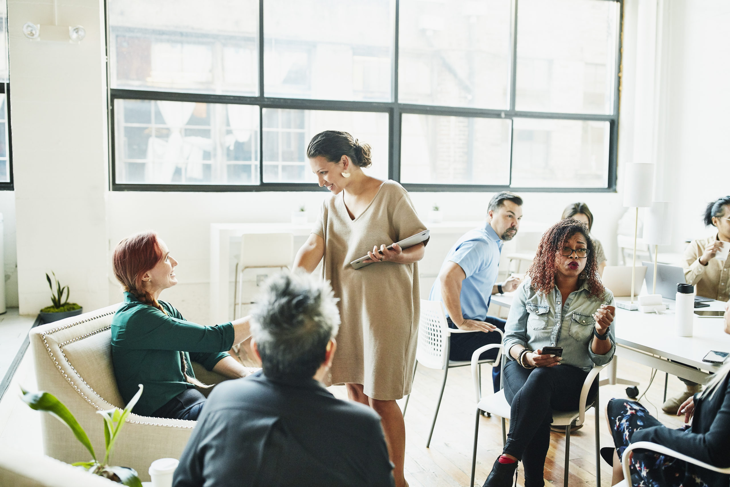 Smiling businesswoman shaking hands with client before team meeting in coworking space 