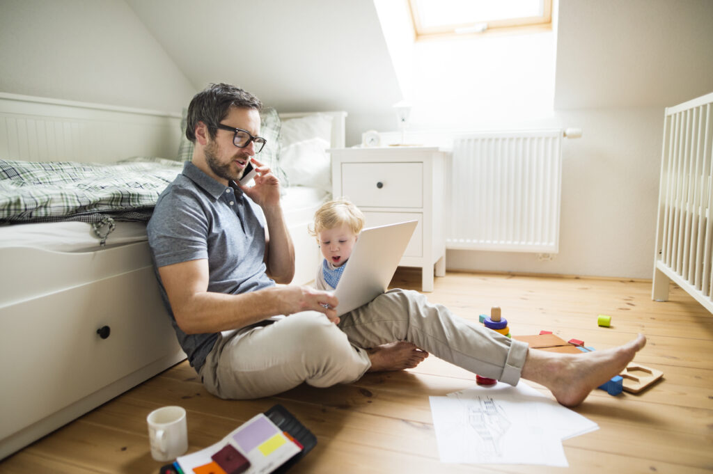 Dad on a work call at a home with his son. 