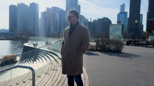 Picture of outsourced HR firm ADDA's founder Adam Daines standing on a pier in Chicago with the skyline behind him