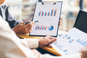 Close up of people examining business data and metrics discussing the cost-effectiveness of outsourced HR