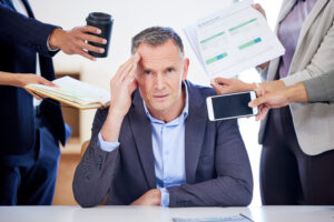 A stressed business owner bombarded with tasks who would benefit from outsourced HR to make his time cost-effective
